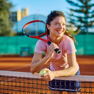 Happy tennis player leaning on net
